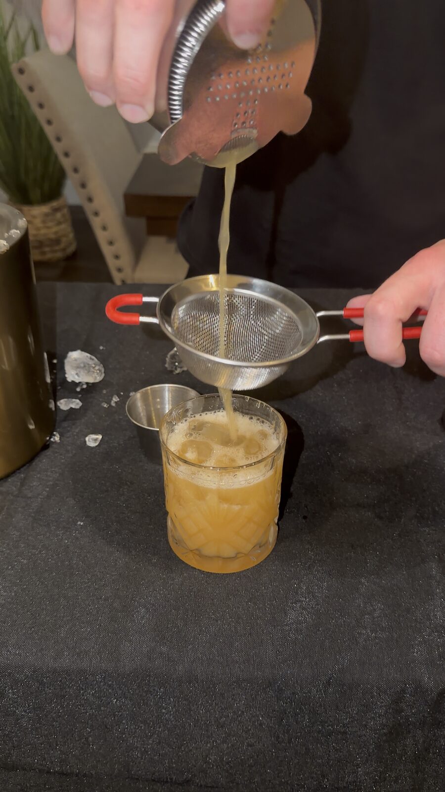Bartender double-straining a freshly shaken cocktail into a glass