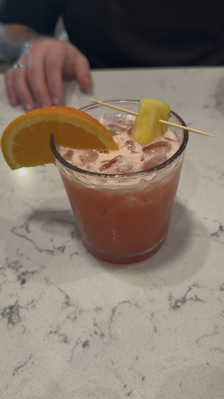 Bright orange pineapple cocktail served over ice