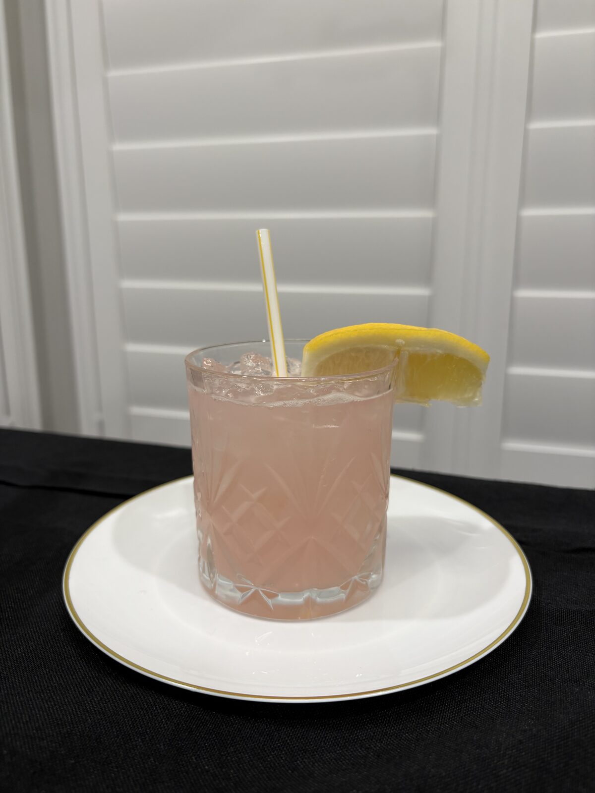 Soft pink signature cocktail with a citrus garnish