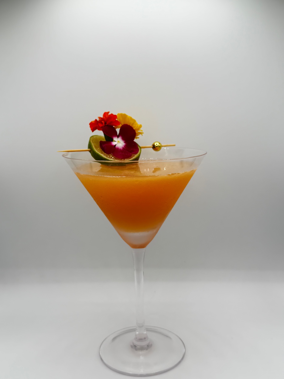 Signature cocktail by Palm Beach Cocktails — garnished with edible flowers and fresh lime