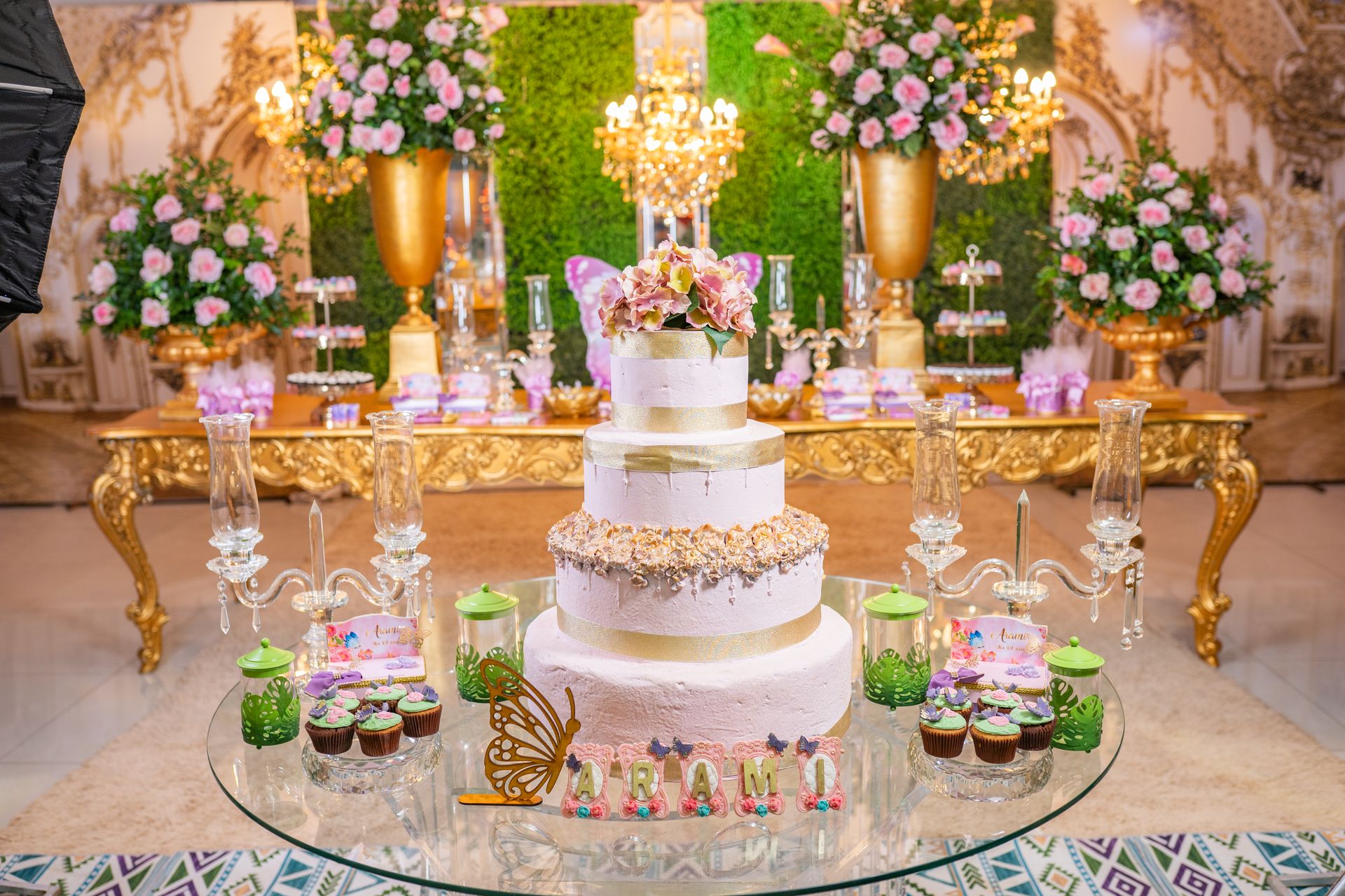 Elegant tiered cake and dessert table with floral and gold decor at a quinceanera celebration